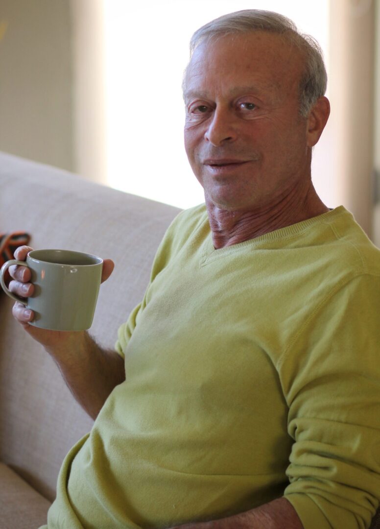 A man sitting on the couch holding a cup.