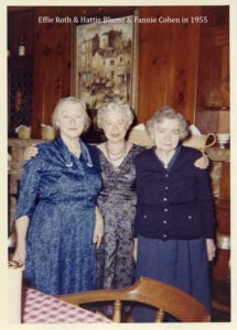 Three women standing next to each other in front of a wall.