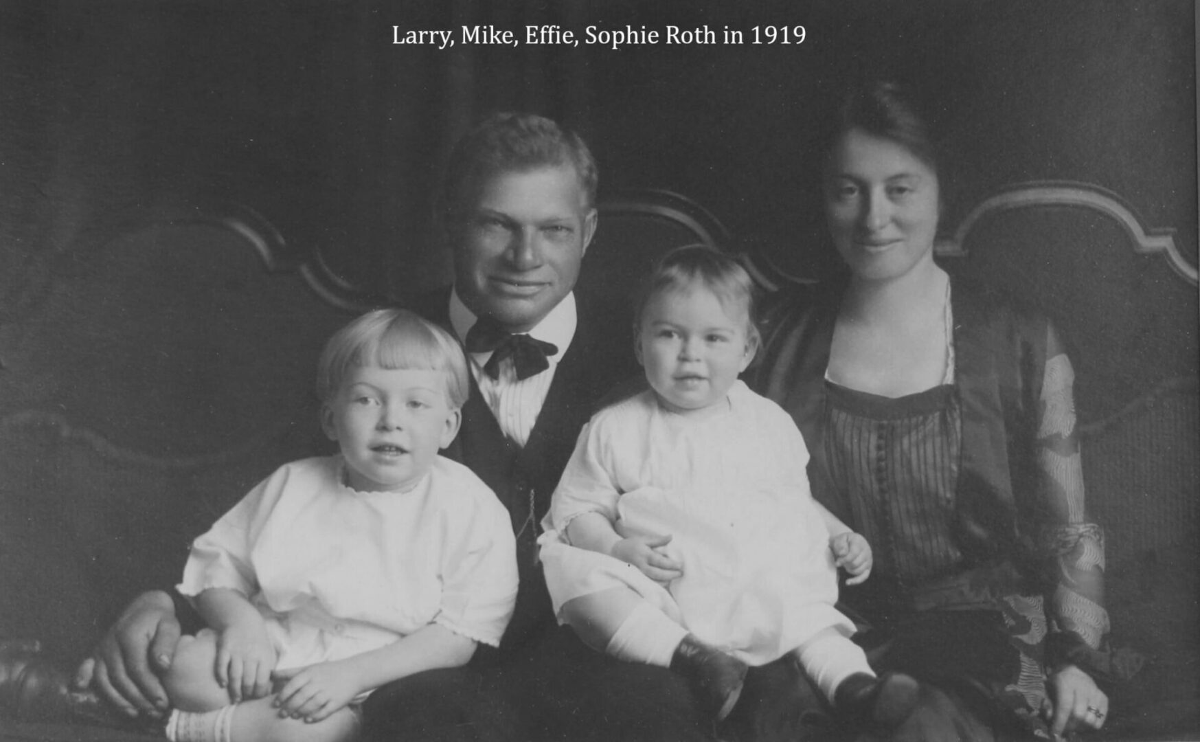 A black and white photo of two men, one holding a baby.