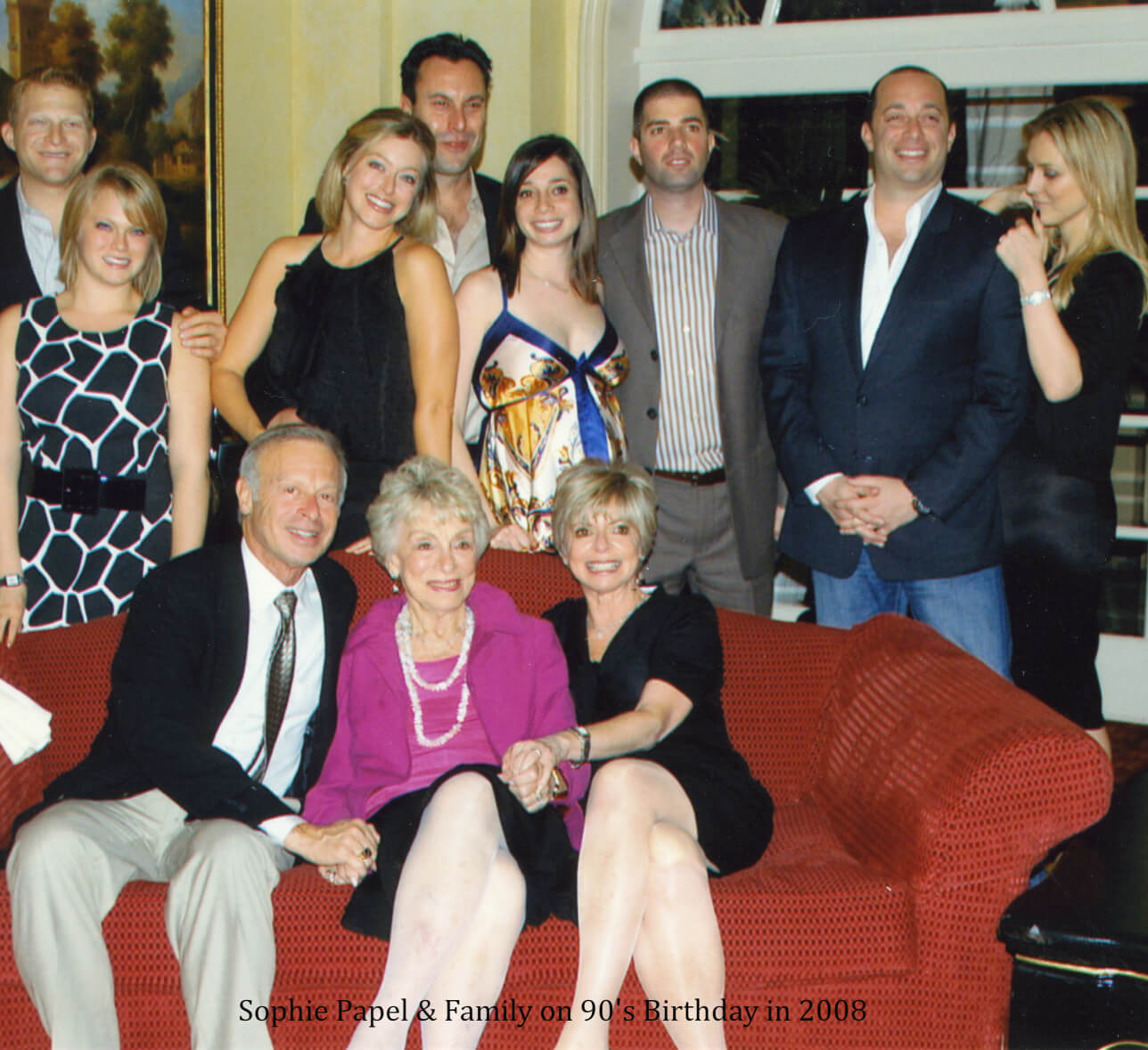 A group of people sitting on top of a red couch.