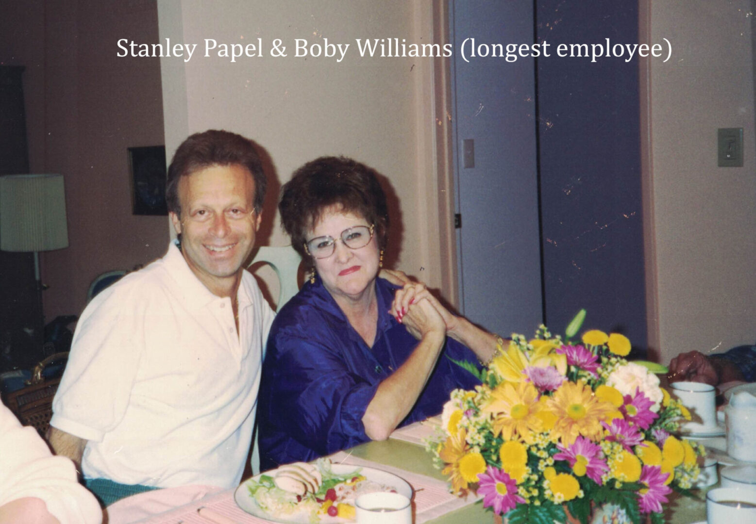 A man and woman sitting at a table with flowers.