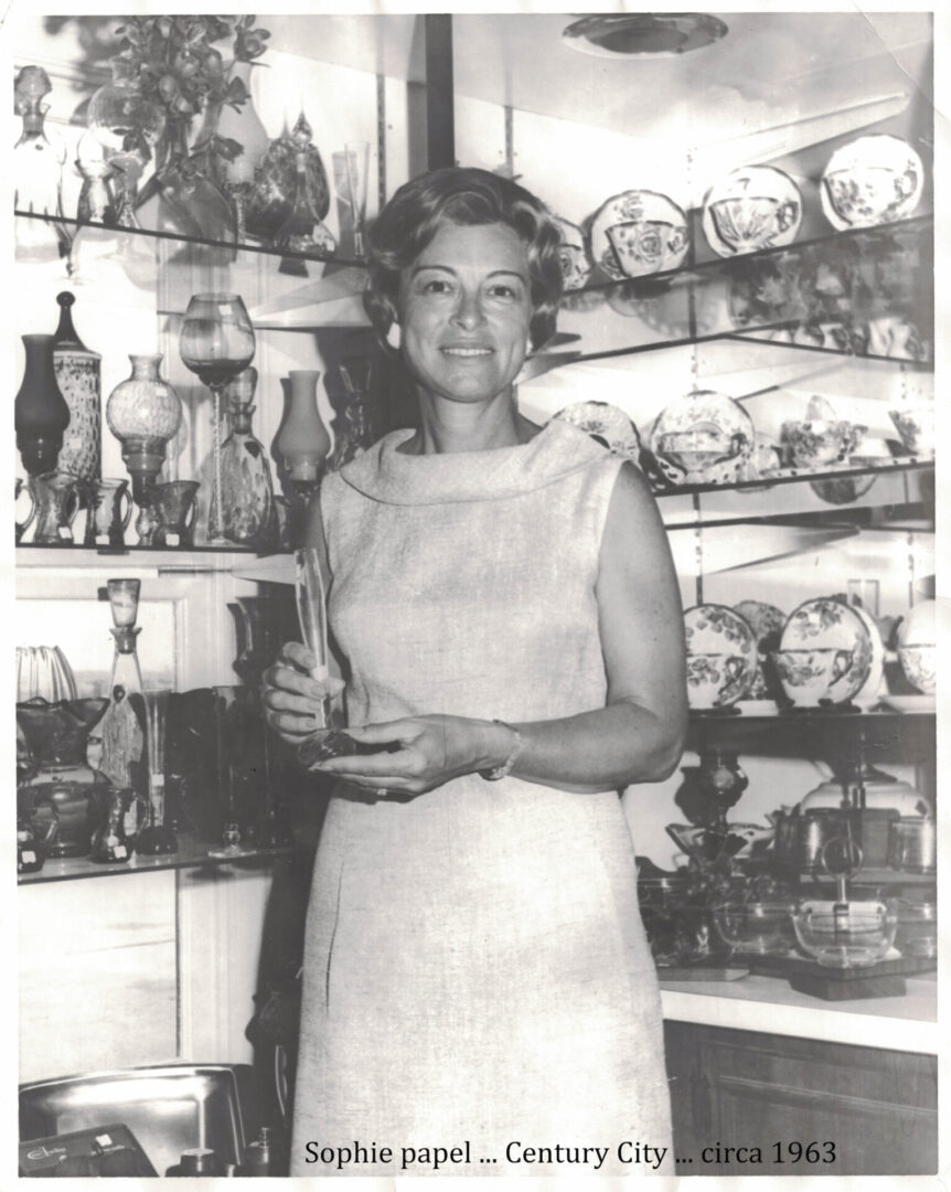 A woman standing in front of shelves filled with glassware.