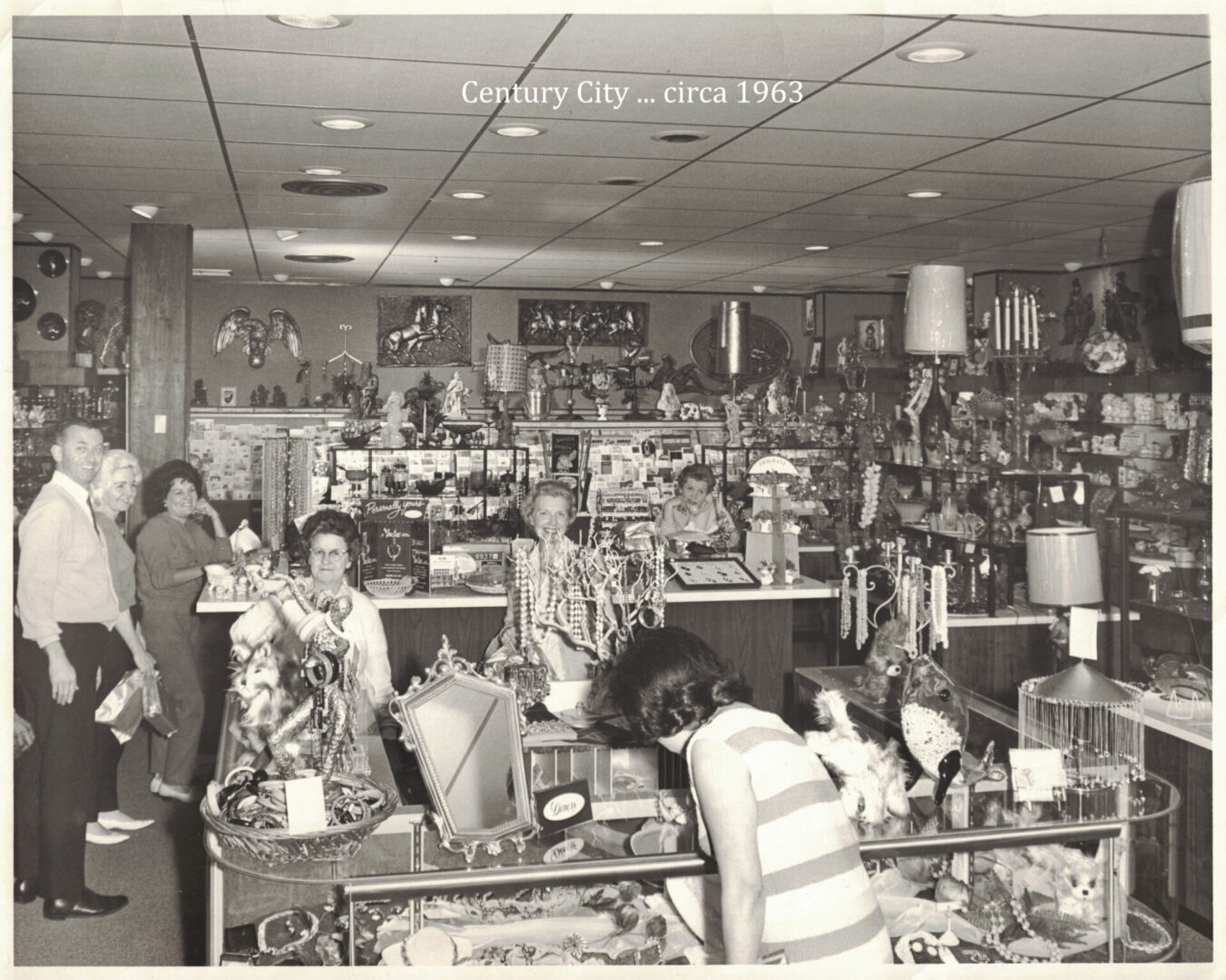 A group of people in a store with many items on the shelves.